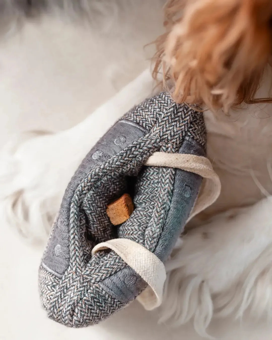 Textured gray and white enrichment dog toy with string on a soft surface