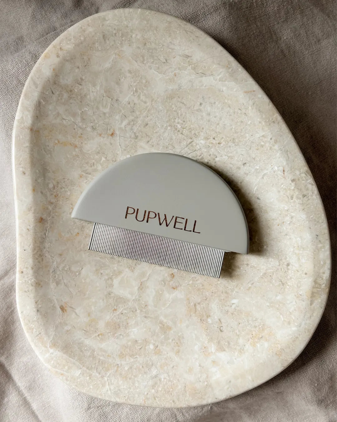 Pupwell grooming tool on a stone surface