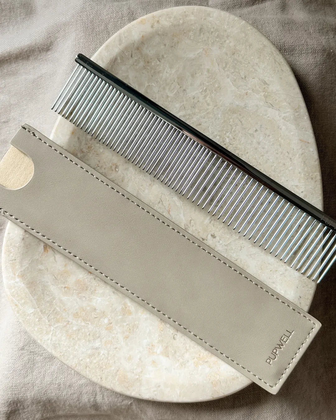Comb with leather pouch on a marble surface