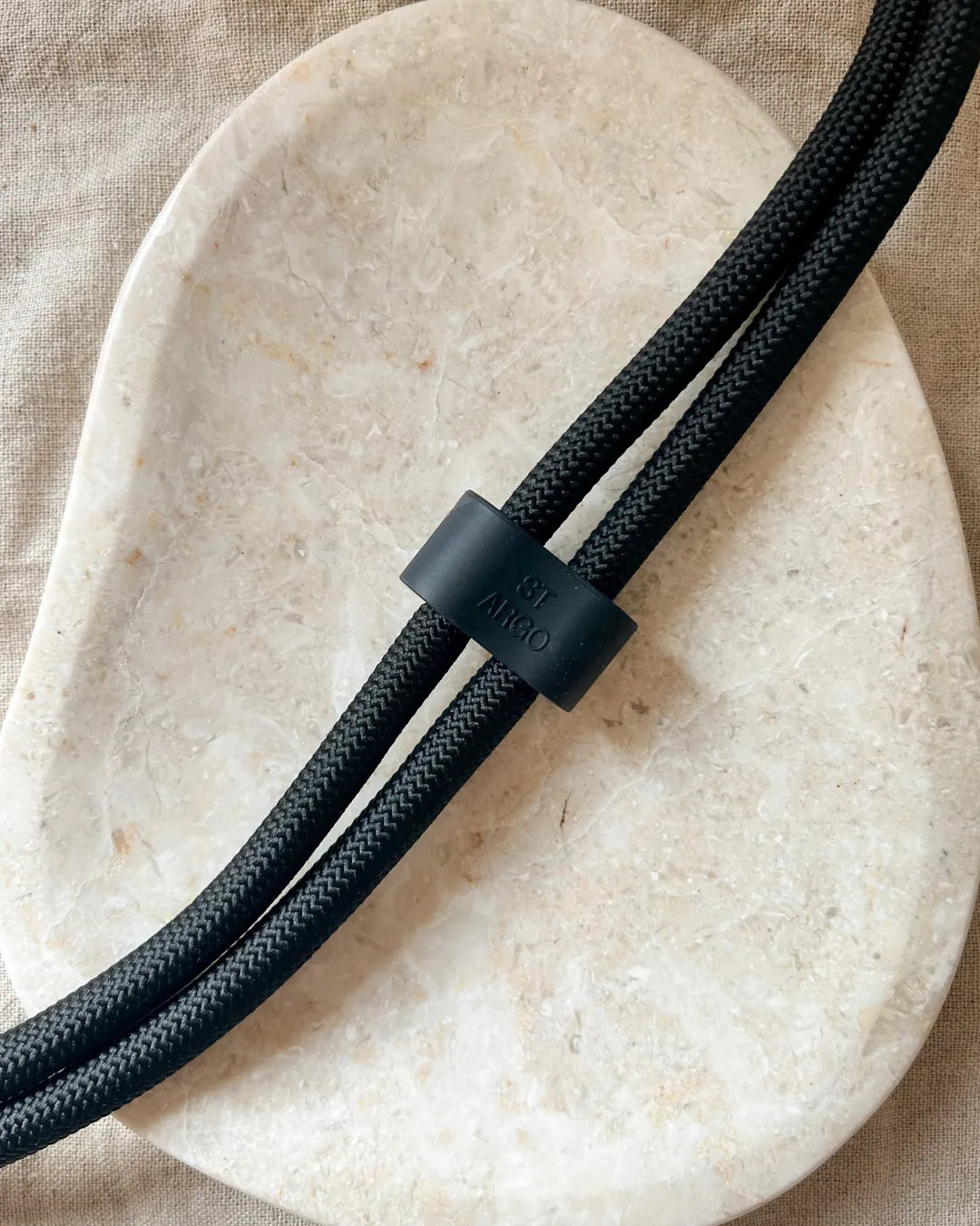 Black luxury rope dog lead with a black clip on a beige stone surface