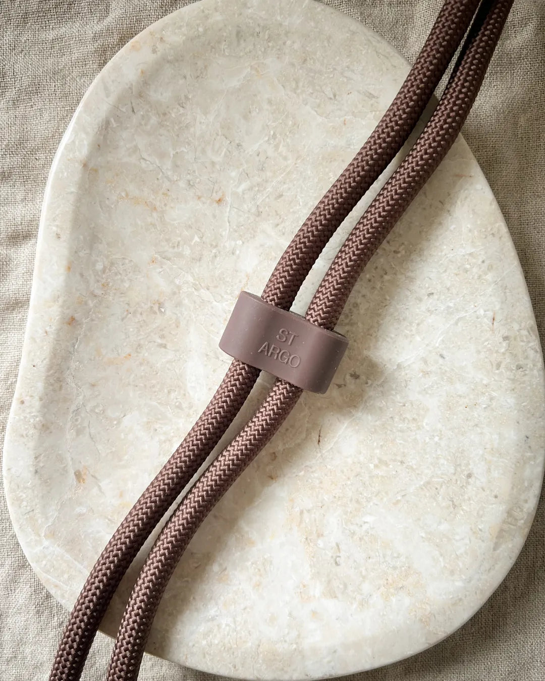 Brown rope luxury handsfree dog lead with a silicone clip on a beige stone surface