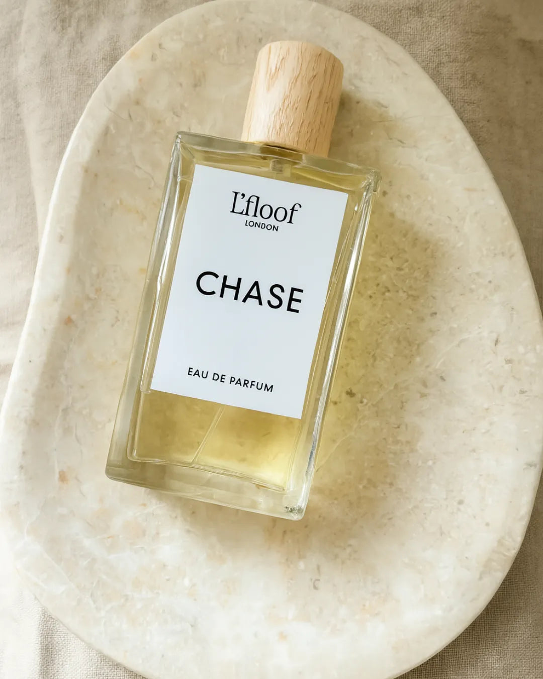 Perfume bottle labeled 'Chase' by L'floof on a beige plate