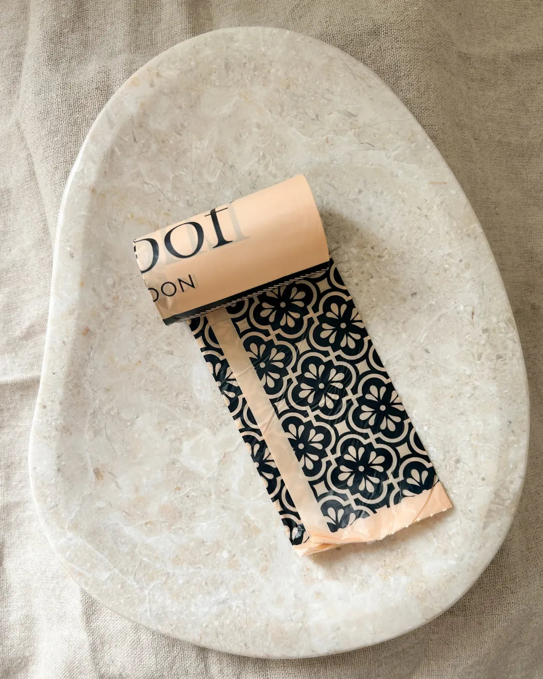 Patterned dog poo bags in a roll on a stone surface