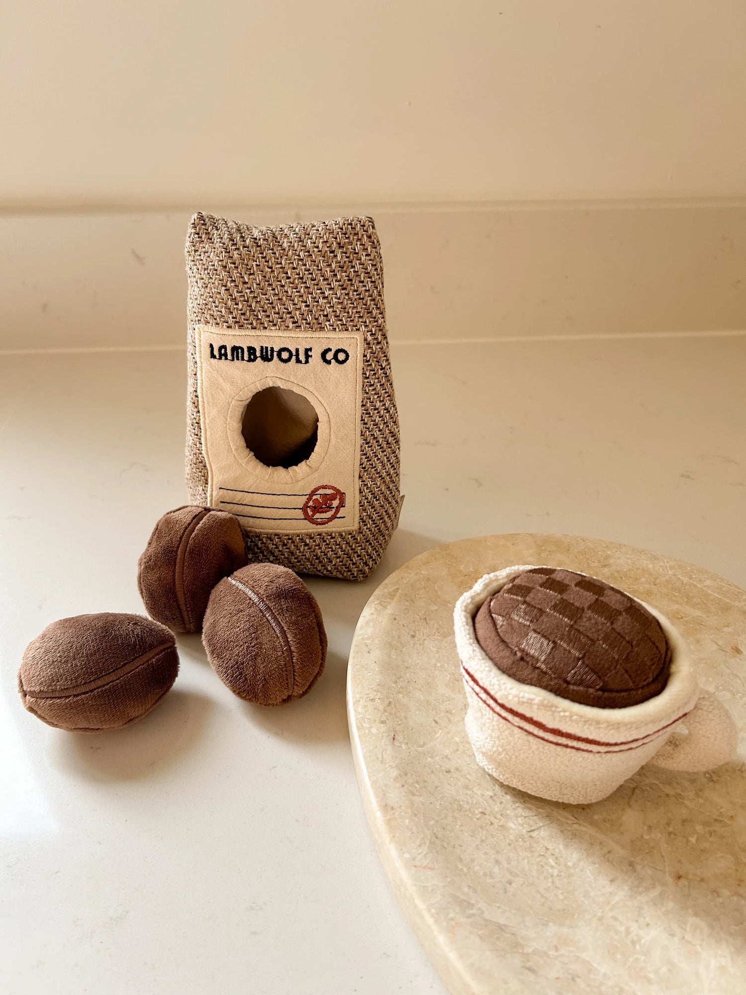 Luxury coffee-themed dog toys on a beige background on marble