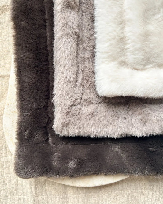 Stack of neutral textured blankets on a neutral background