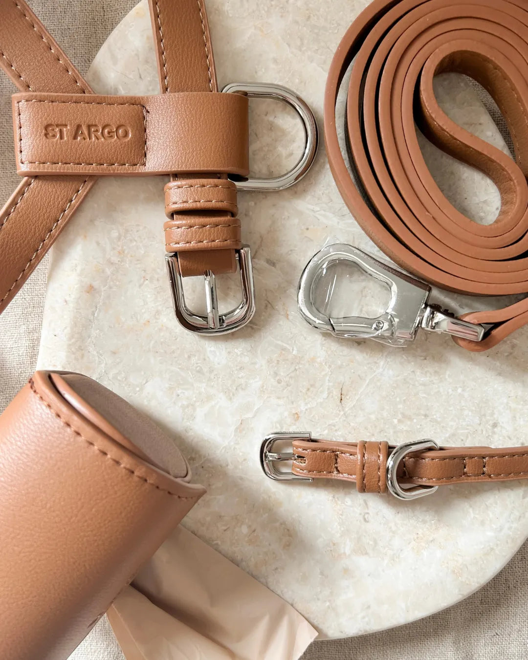 Brown luxury vegan leather dog harness, lead, and collar on a textured surface with 'ST ARGO' branding.
