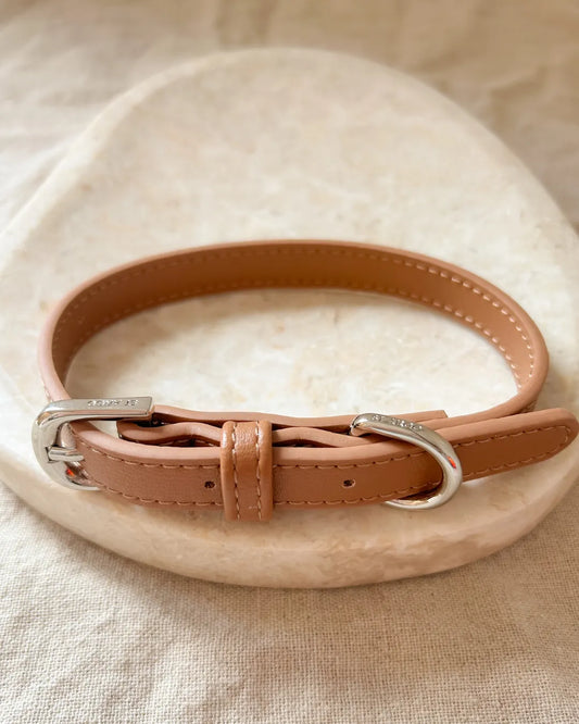 Brown luxury vegan leather dog collar with silver buckle on a beige surface
