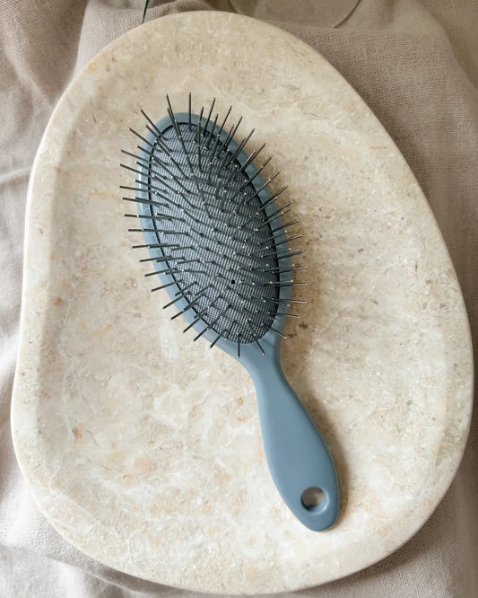 Grey hairbrush on a stone surface
