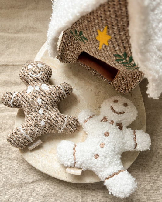 Two dog toy gingerbread men on a beige marble surface with a textured background