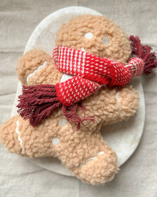 Plush gingerbread man dog toy with a red and white checkered scarf on a neutral background