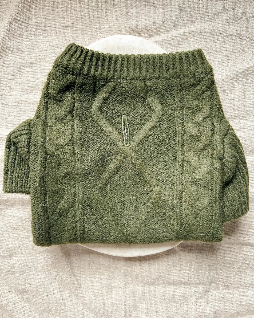 Green knitted dog jumper on a light grey background