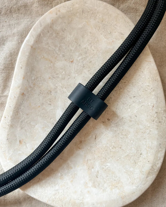 Black luxury rope dog lead with a black clip on a beige stone surface