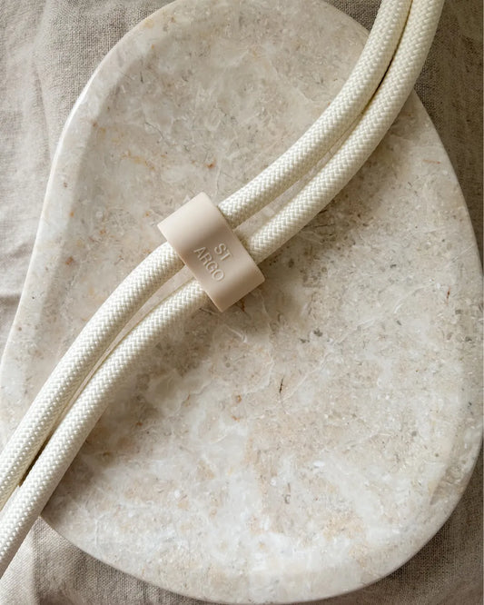 Beige luxury handsfree lead with a taupe silicone adjuster on a beige stone surface