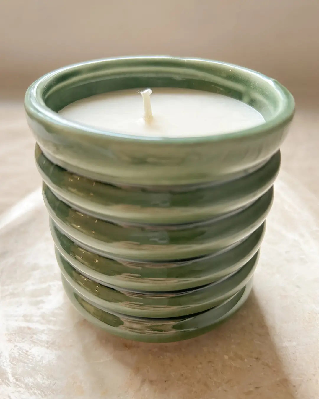 Green ceramic candle on a light marble background