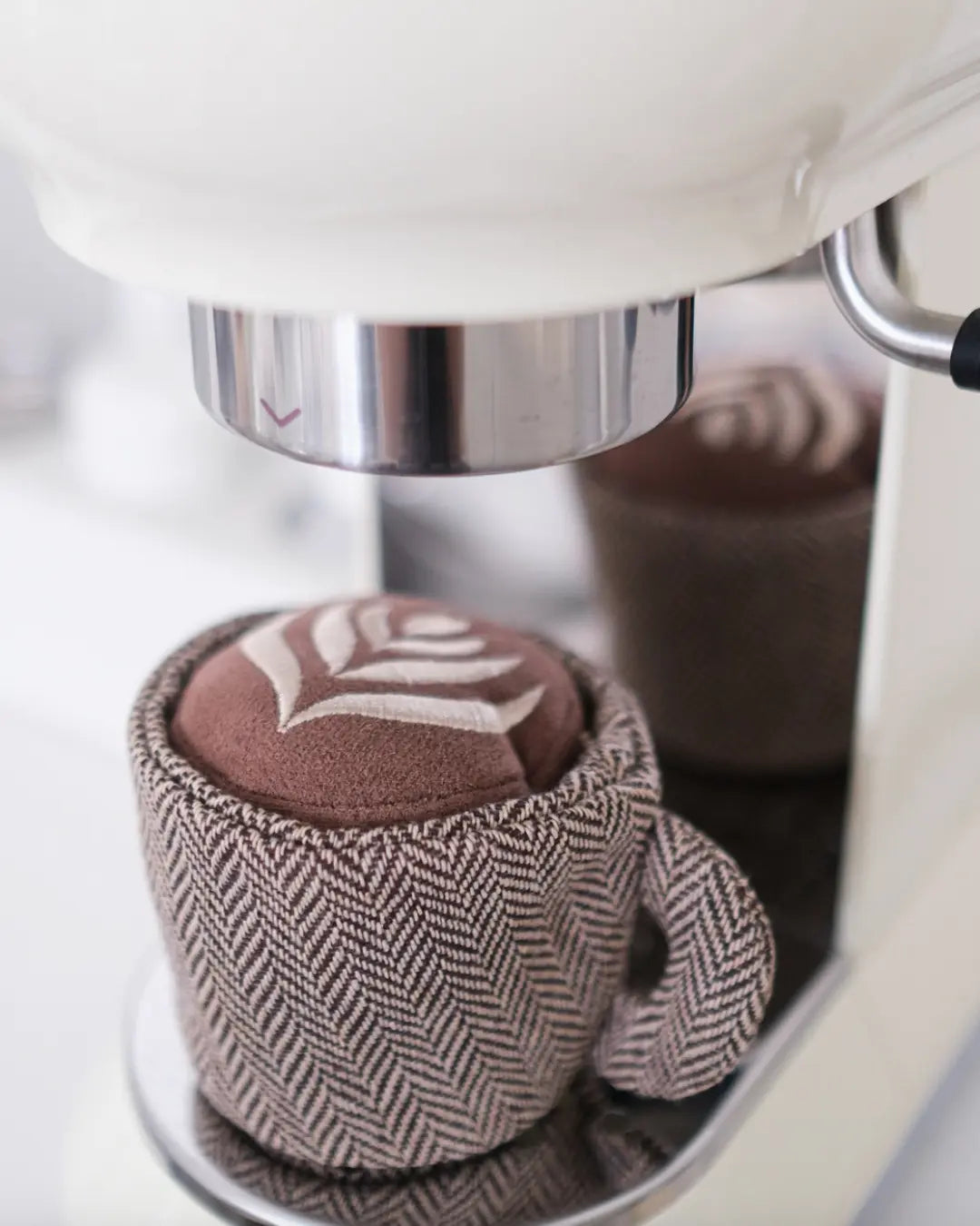 Plush latte-shaped dog toy on a coffee machine