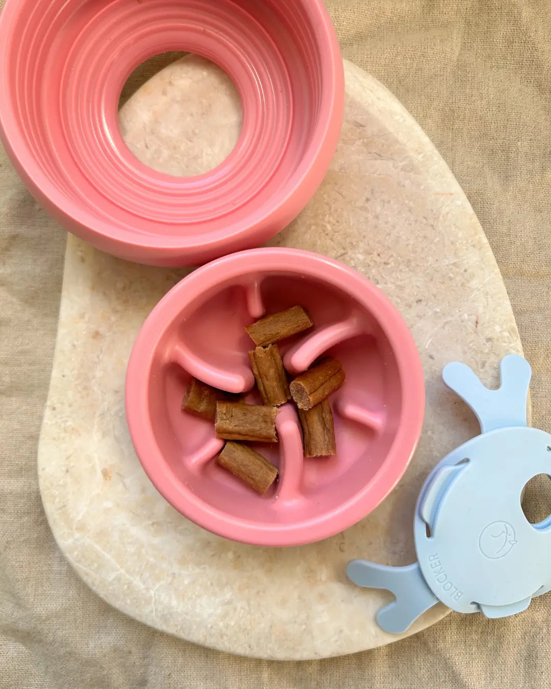 Pink and blue dog enrichment slow feeder and treat dispenser on a neutral background