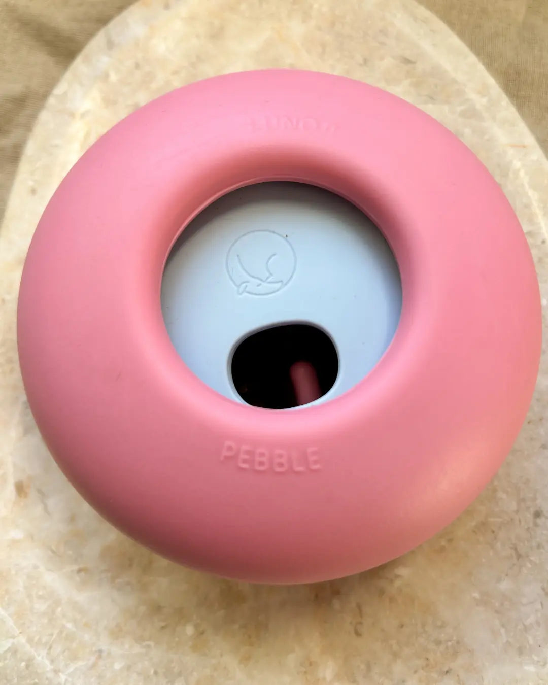 Pink and light blue Lunoji pebble slow feeder and treat dispenser on a neutral background