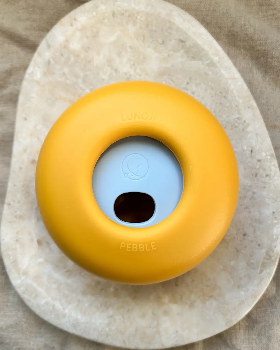 Yellow and light blue Lunoji slow feeder and treat dispenser on a neutral background