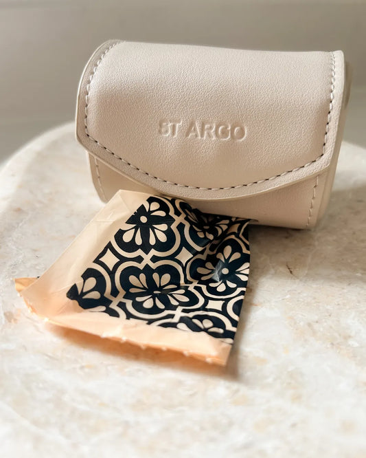 Beige dog poo bag holder with a patterned poo bag on a textured surface