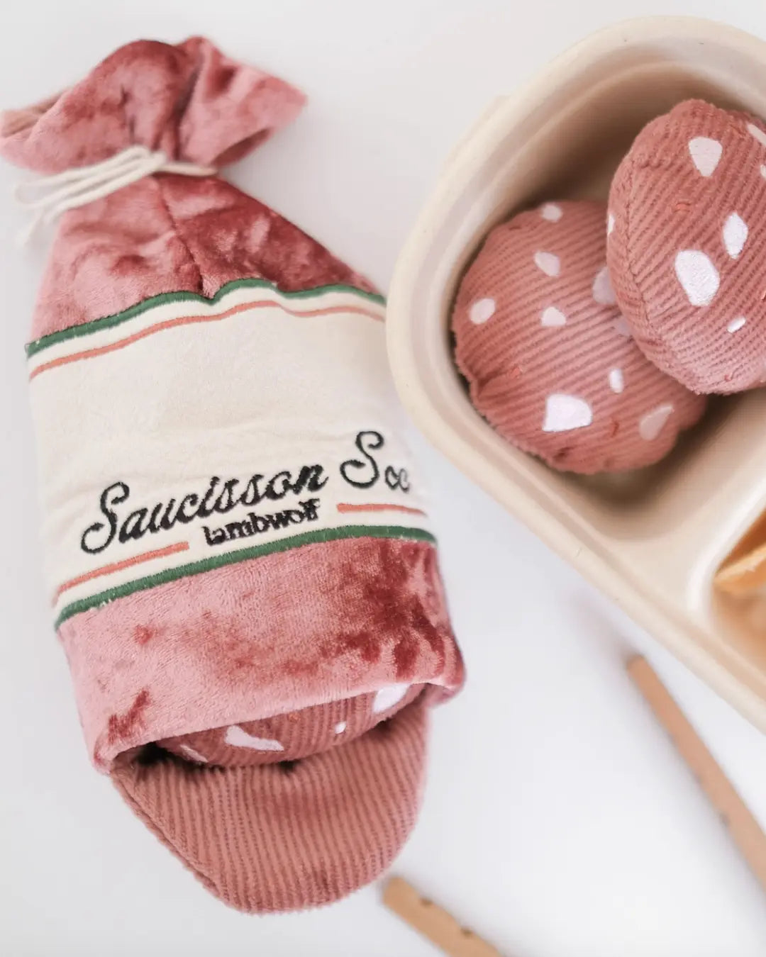 Saucisson sec-shaped dog toy on a white background with plush salami toys nearby