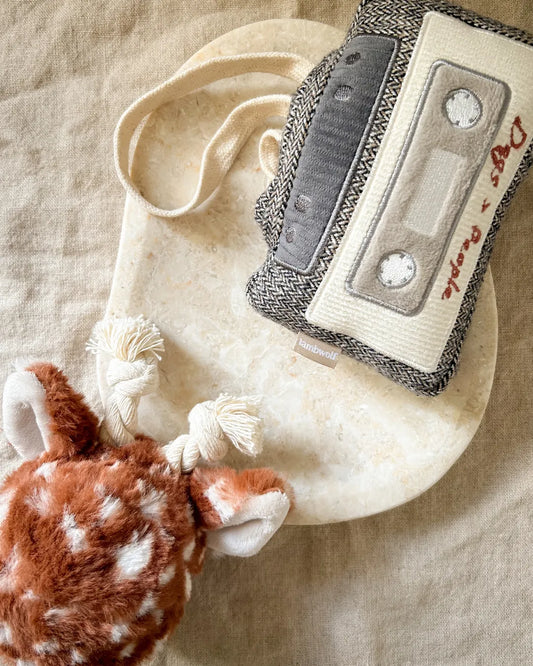 Plush vintage cassette dog toy and a plush deer toy on a neutral background