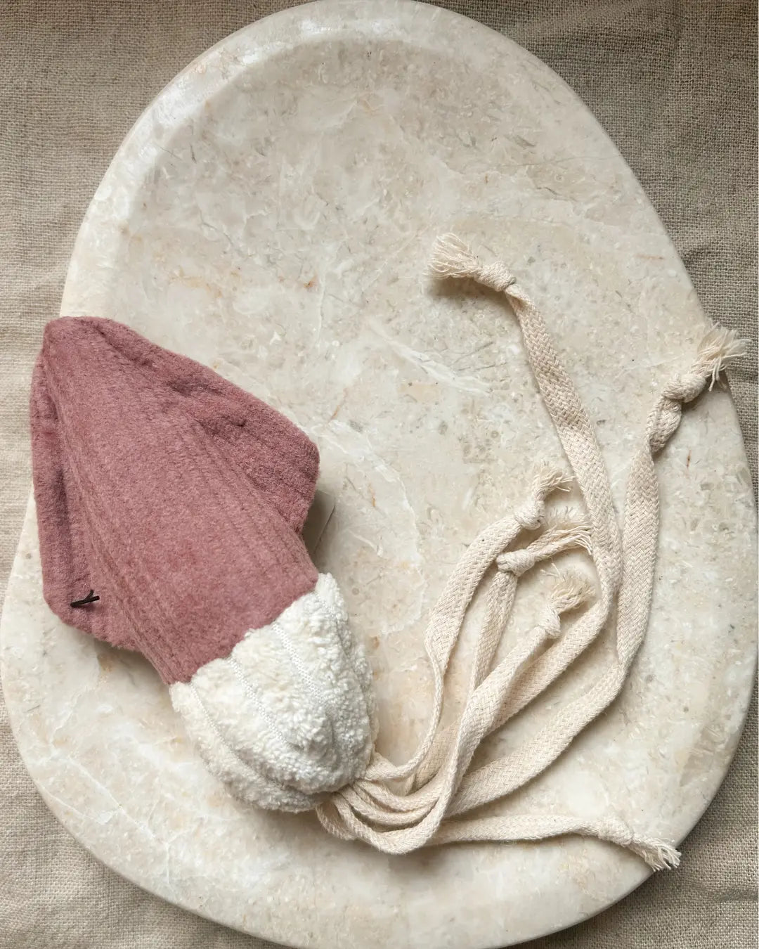 Red and white squid-shaped dog toy on a beige marble background