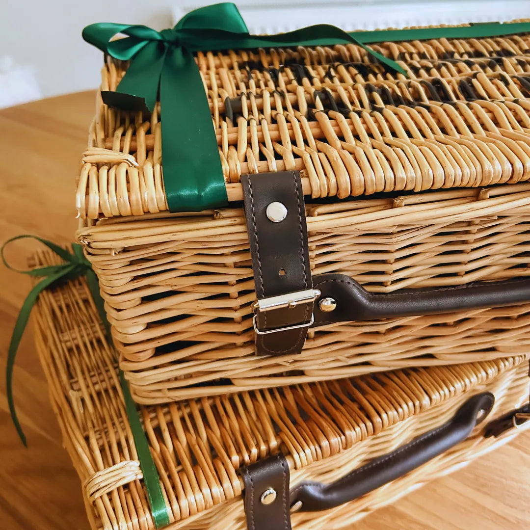 Luxury wicker hamper with a green ribbon on a wooden surface