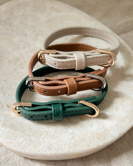 Three vegan leather luxury dog collars in beige, brown and green on a marble surface