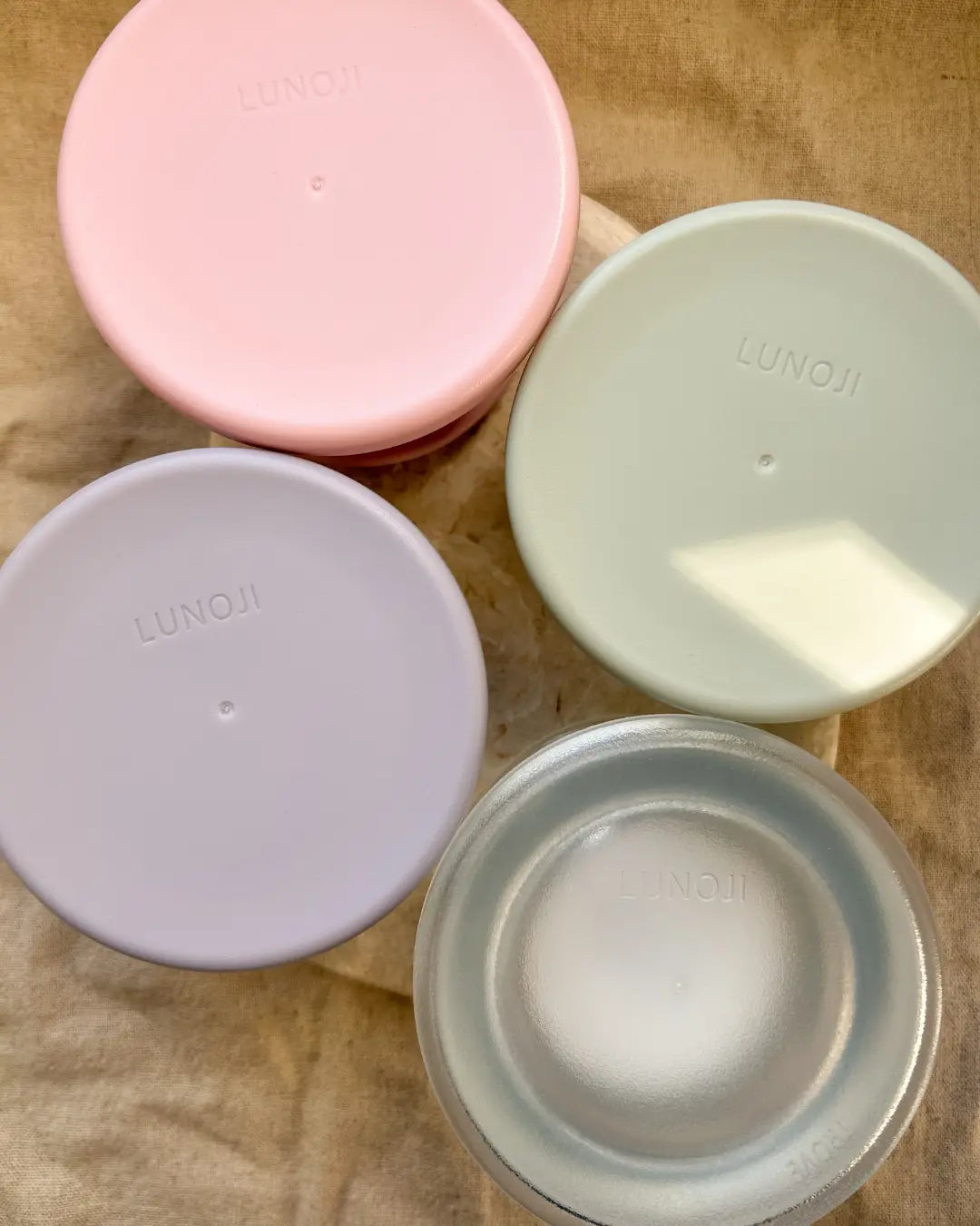 Four dog enrichment bowls in pink, sage, lilac and clear on a neutral background