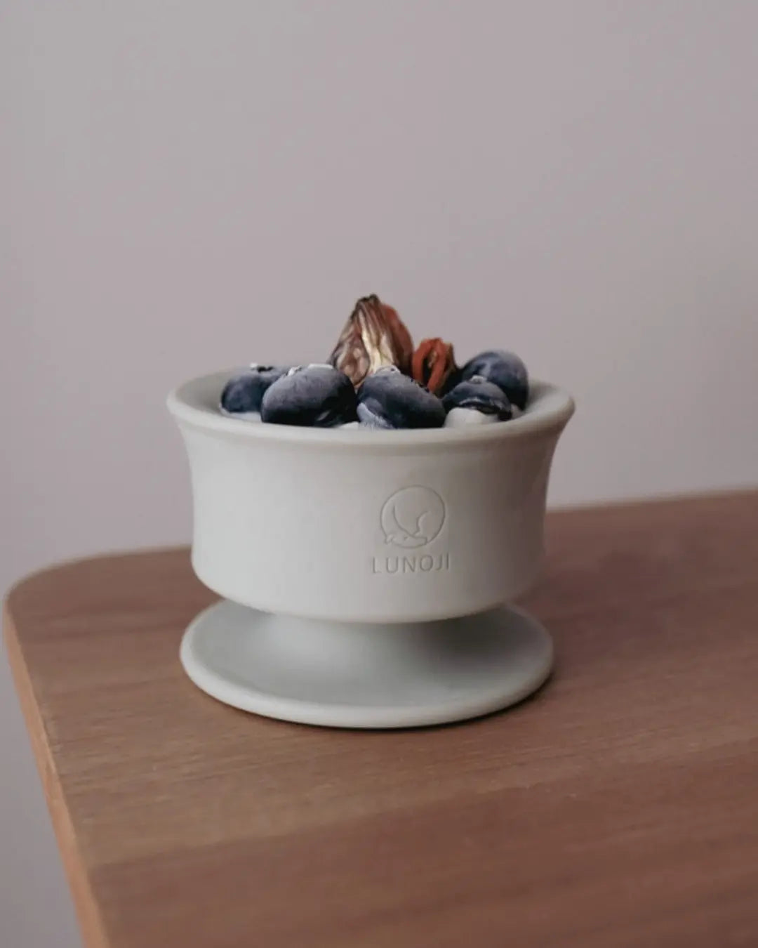 Sage green enrichment bowl filled with frozen dog treats on a wooden table