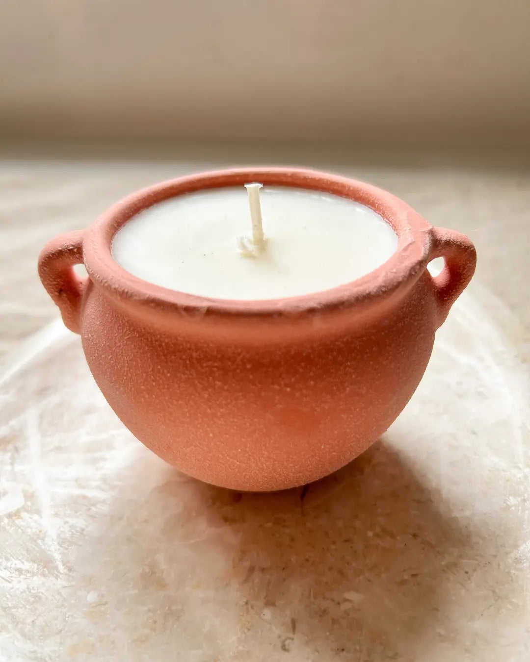 Candle in a terracotta pot on a textured surface