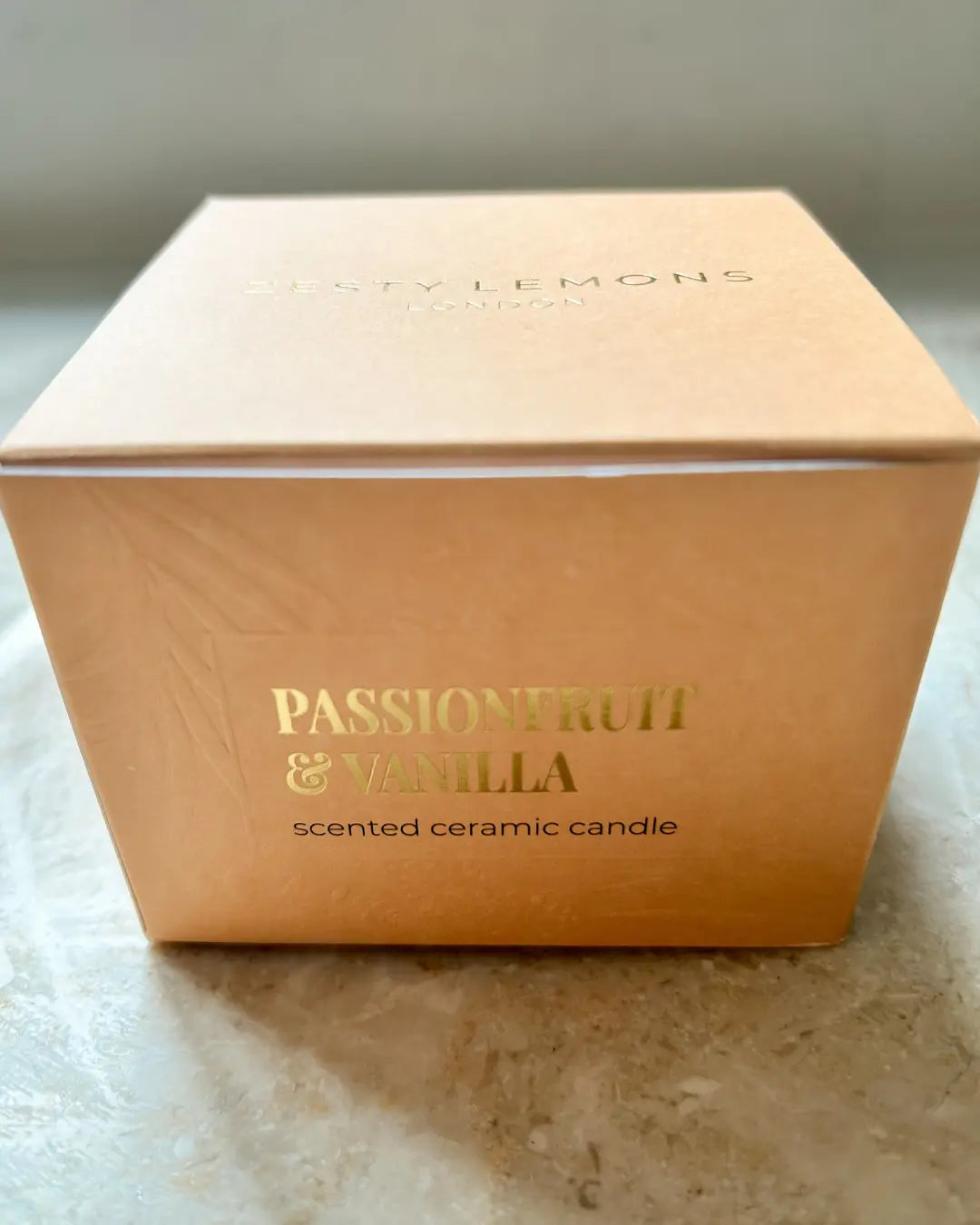 Candle box with 'Passionfruit & Vanilla' fragrance on a marble surface