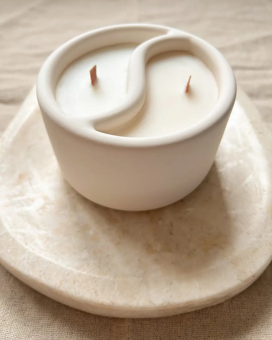 White candle in a decorative holder on a beige surface